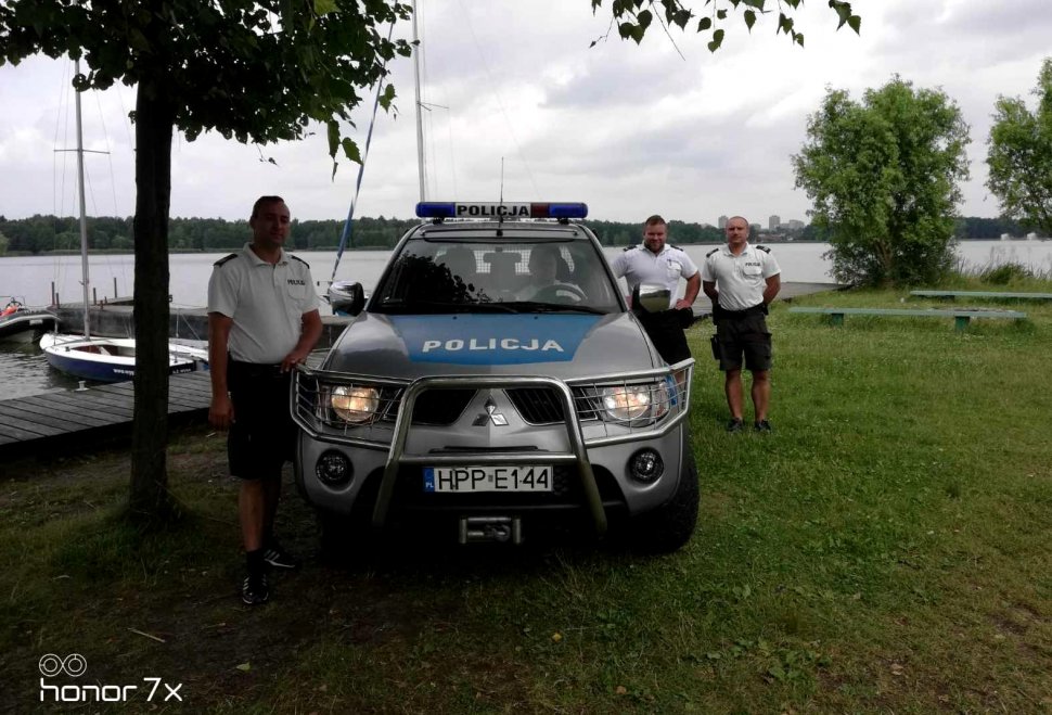 Na zdjęciu obo radiowozu stoji troje policjantów patrolu policcji wodnej. 