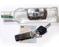 Obrazek przedstawia butelkę alkoholu i kluczyki od samochodu położone na dowodzie rejestracyjnym pojazdu