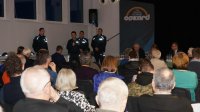 Obrazek przedstawia siedzących ludzi &quot;tyłem&quot; oraz czterech policjantów podczas debaty społecznej
