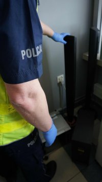 Obrazek przedstawia policjanta w kamizelce odblaskowej, który trzyma głośniki z kina domowego odzyskanego z włamania