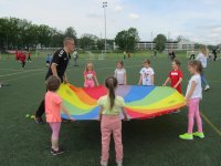 Obrazek przedstawia dzieci na boisku trzymające kolorowe kółko