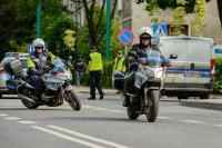 Obrazek przedstawia policjantów na motocyklach, a w tle funkcjonariuszy straży miejskiej i ich radiowóz