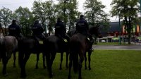 Obrazek przedstawia czterech policjantów na koniach stojących tyłem do zdjęcia, a przodem do tyskiego stadionu