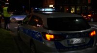 Obrazek przedstawia policjanta i radiowóz na skrzyżowaniu nocą