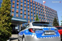 Obrazek przedstawia radiowóz, w tle widoczny budynek Komendy Wojewódzkiej Policji w Katowicach