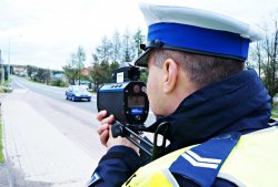 Zdjęcie przedstawia policjanta z wydziału ruchu drogowego, który mierzy prędkość