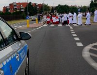 Na zdjęciu widoczny radiowóz oraz ministrantów prowadzących uczestników procesji Bożego Ciała