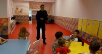 Na zdjęciu widoczny policjant, który prowadzi prelekcje z dziećmi na temat bezpieczeństwa.
