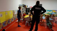 Na zdjęciu widoczny policjant, który prowadzi prelekcje z dziećmi na temat bezpieczeństwa.