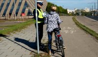 Policjant bz drogówki rozmawia z rowerzystką i daje jej opaskę odblaskową.