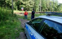 Radiowóz oraz funkcjonariusz Policji wraz z przedstawicielem PLK stoją na &quot;dzikim przejściu&quot; w rejonie torów kolejowych.