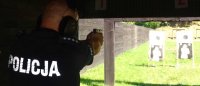 Umundurowany policjant strzela z broni służbowej podczas szkolenia na strzelnicy.