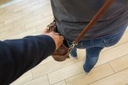 kobieta z torebką na ramieniu, za nią mężczyzna, który niezauważony zabiera jej portfel z torebki