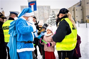 Na zdjęciu policjant, strażnicy miejscy oraz Mikołaj rozdający odblaski.