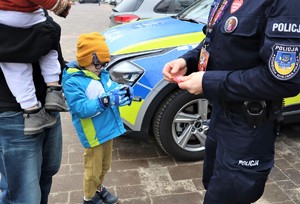 Na zdjęciu policjant oraz dziecko z opiekunem podczas obchodów 32. Finału Wielkiej Orkiestry Świątecznej Pomocy.