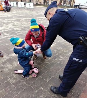 Na zdjęciu policjant oraz dziecko z opiekunem podczas tyskiego 32. Finału Wielkiej Orkiestry Świątecznej Pomocy.