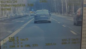 Zdjęciu przedstawiające wideorejestrator, który zarejestrował przekroczenie prędkości. Na wyświetlaczu widoczna prędkość jadącego przed radiowozem samochodu, wskazująca 156,5 kilometra na godzinę.